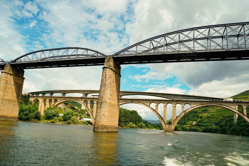 A stone bridge with multiple arches over a river, surrounded by greenery and hills. 5