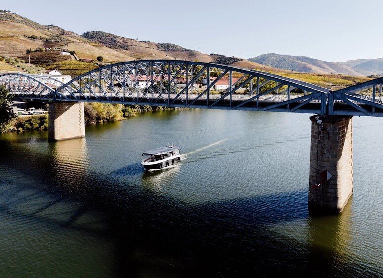A river with a boat, a bridge, and hills in the background. 2