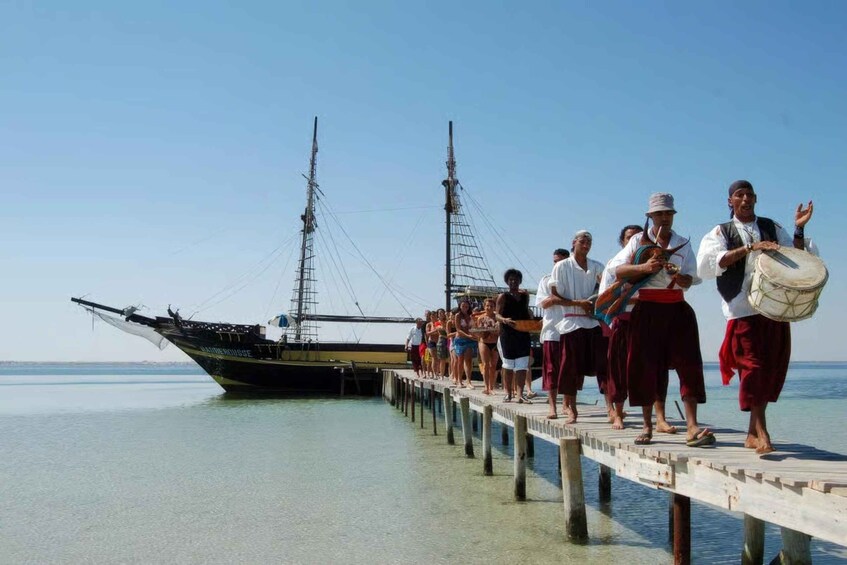 A group of people on a wooden pier by a boat named 'SAIDENHOUSE' in a calm sea. 4