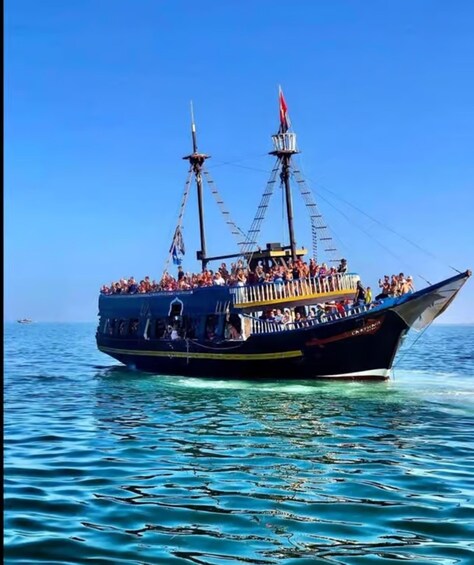 A large boat with multiple decks filled with people, sailing on a calm sea. 2