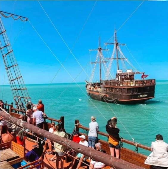 A large sailing ship docked at a pier with people on board and on the pier. 1