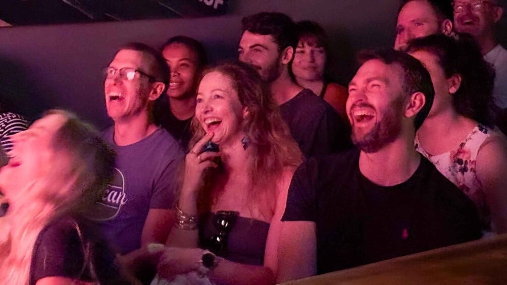 A group of people at a social event, likely a party or concert, with dim lighting and a crowd gathered closely together. 4