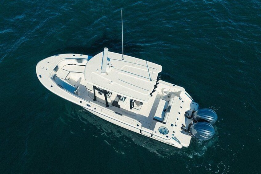 A white motorboat with a cabin, a mast, and two outboard motors on the water. 3