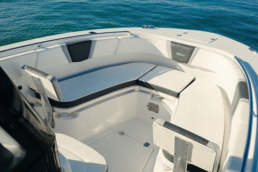 A boat's interior with a white hull, a seating area, and a control panel. 2