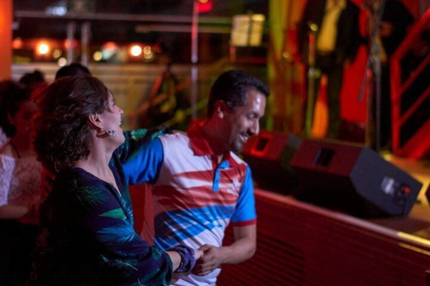 A person in a striped polo shirt and a woman in a patterned top at an amusement park ride. 1