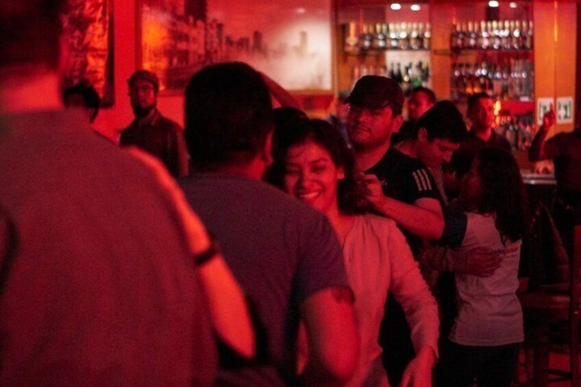 A crowded bar with people standing and conversing. 5