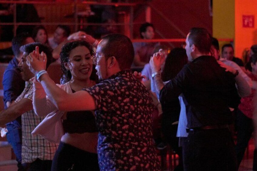 People dancing in a dimly lit room with red lighting. 2