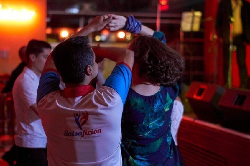 Two people dancing in a dimly lit room with red lighting. 4