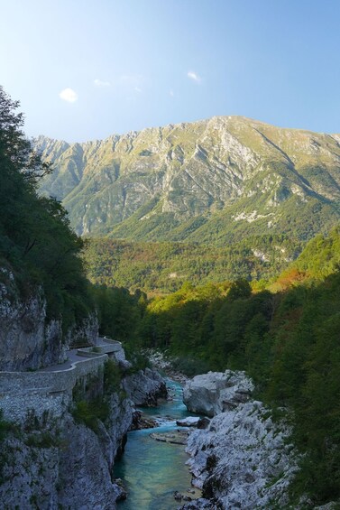 A mountain landscape with a river, rocky cliffs, and a winding road. 2