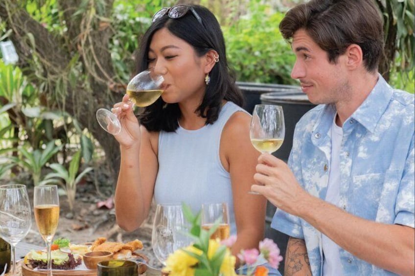 Two people at an outdoor dining table with wine glasses and a variety of dishes. 1