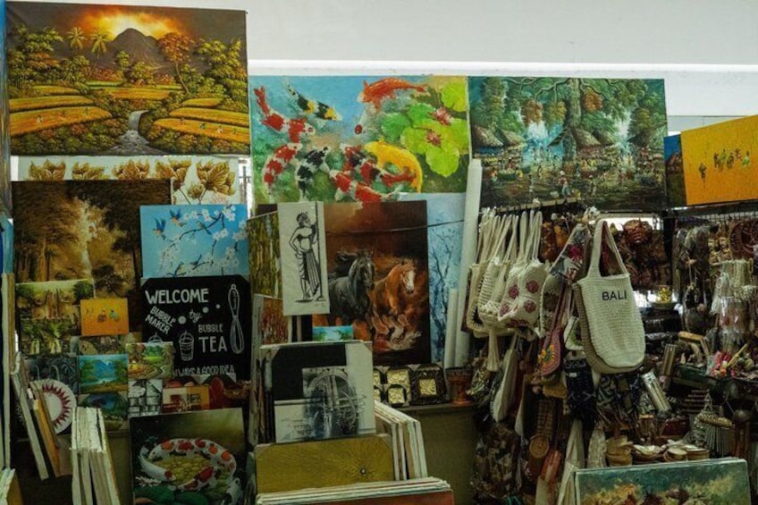 A display of paintings and bags with 'BALI' written on them. 2