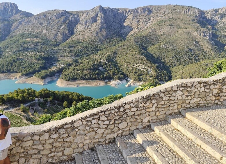 Una escalera de piedra que lleva a un mirador con vistas a un lago turquesa y terreno montañoso. 3