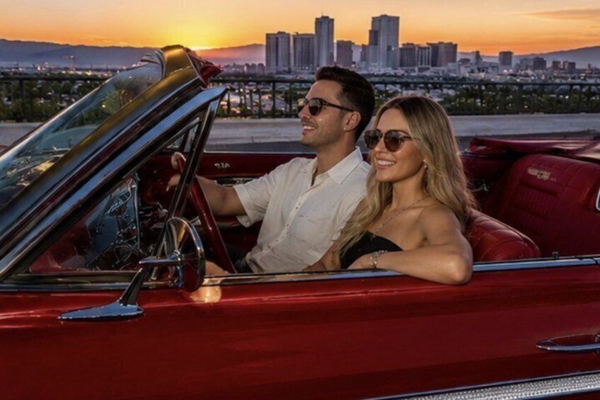 A red convertible with a city skyline in the background. 1