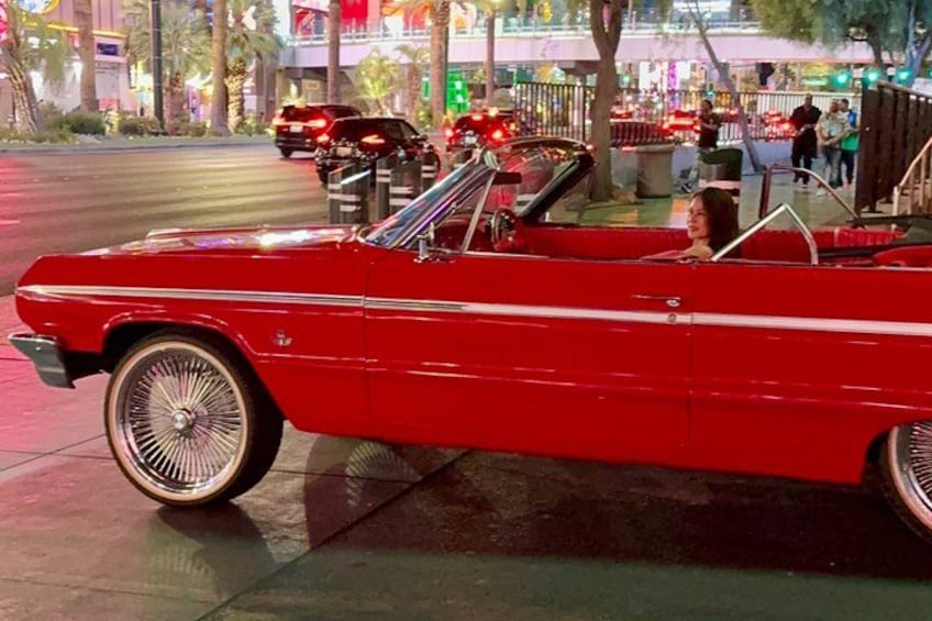 A red vintage convertible car parked on a sidewalk. 3