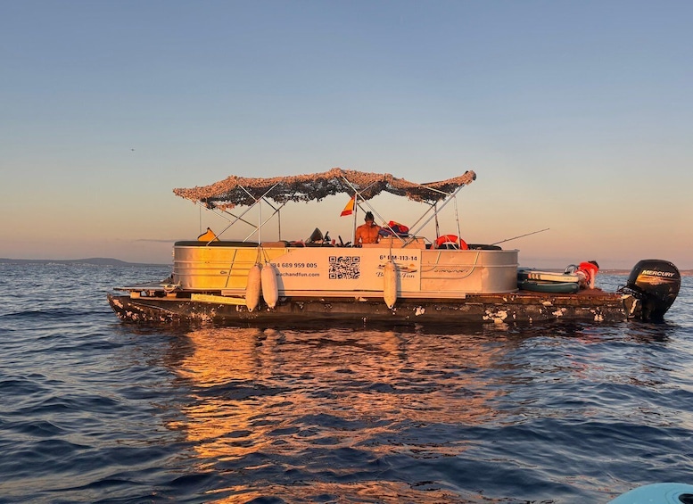 A boat with a canopy and a QR code, floating on calm water during sunset. 2
