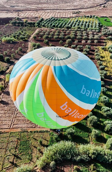 A colorful hot air balloon with the text 'balloon' and 'CN-CMD' over a landscape with terraced fields and sparse vegetation. 4