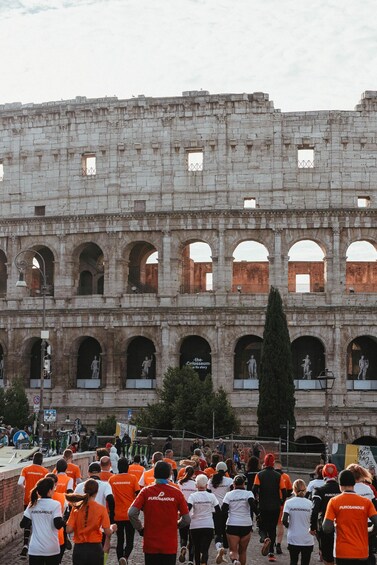 A crowd of people running in front of an ancient Roman amphitheater. 5