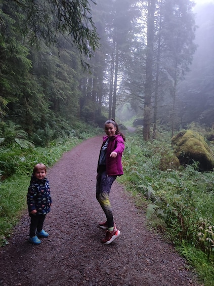 A woman and a child walking on a forest path surrounded by trees and greenery. 5