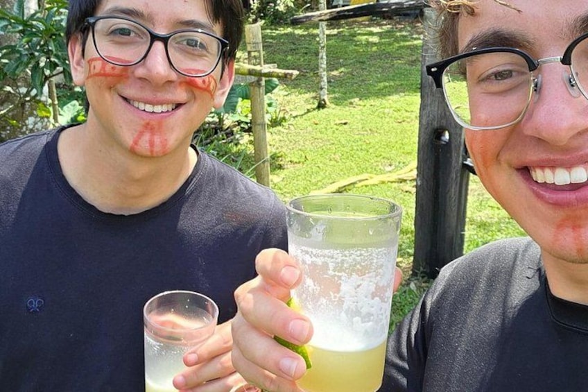 Two people holding drinks outdoors with greenery in the background. 3