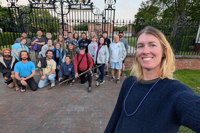 A group of people posing in front of a wrought iron gate. 2