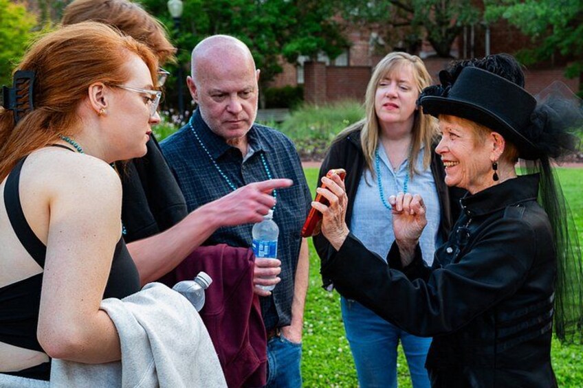 A group of people outdoors, some holding drinks, in a casual gathering. 4