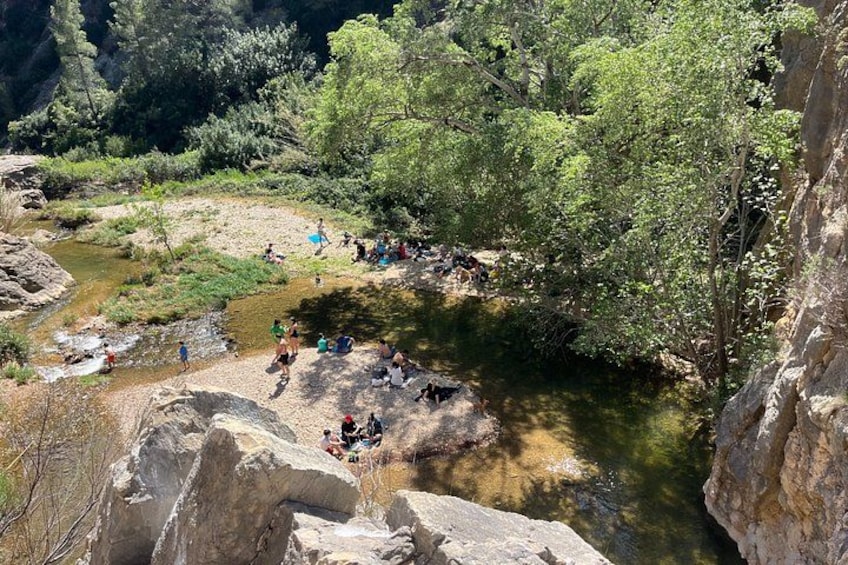 A group of people near a river in a rocky canyon with trees. 3