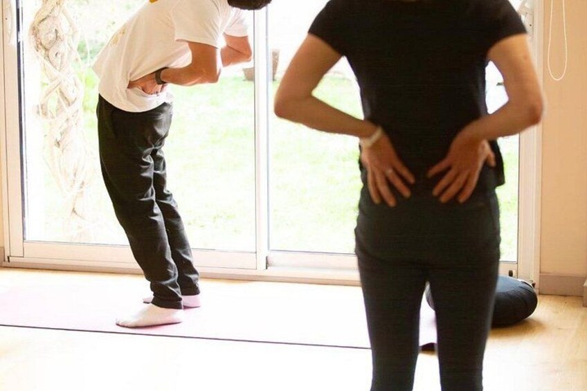 Two people in a room with a large window, one bending over and the other standing with hands on hips. 5