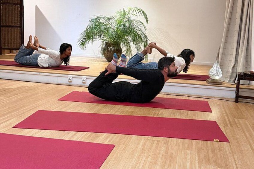 A yoga class in a room with wooden floors and red mats. 1