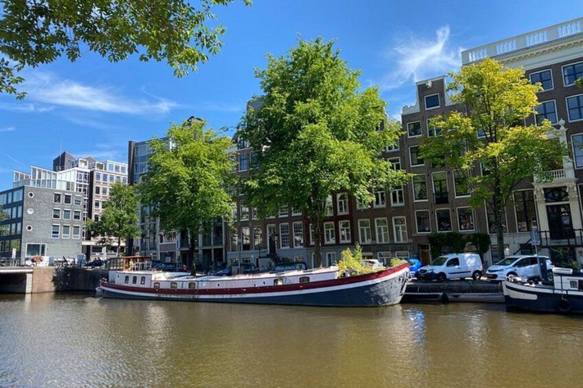 A canal with a boat, buildings, and trees. 2