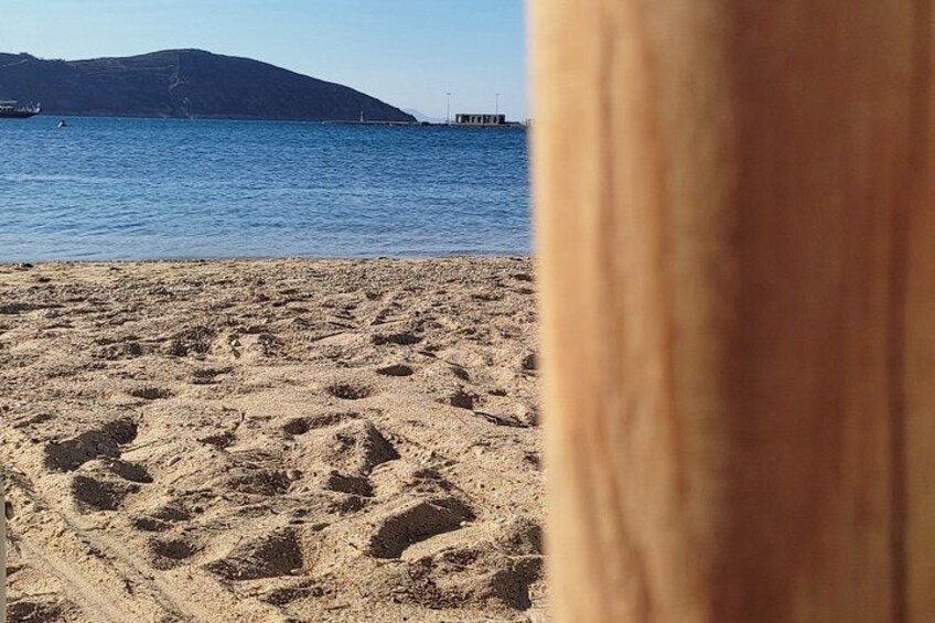 A sandy beach with footprints, a body of water, and a distant mountain. 2