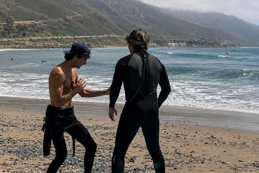 Two people on a beach with ocean and mountains in the background. 2