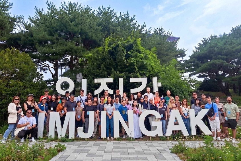 A group of people standing in front of large Korean letters spelling 'IMJINGAK.' 5