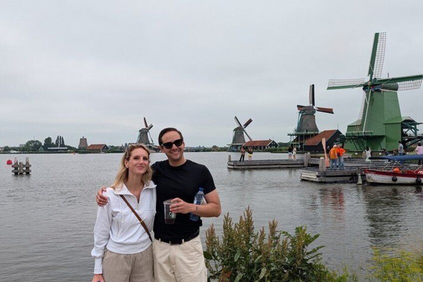 A couple standing by a body of water with windmills in the background. 2