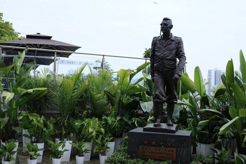 A statue of a man in uniform, surrounded by potted plants and a gazebo. 5
