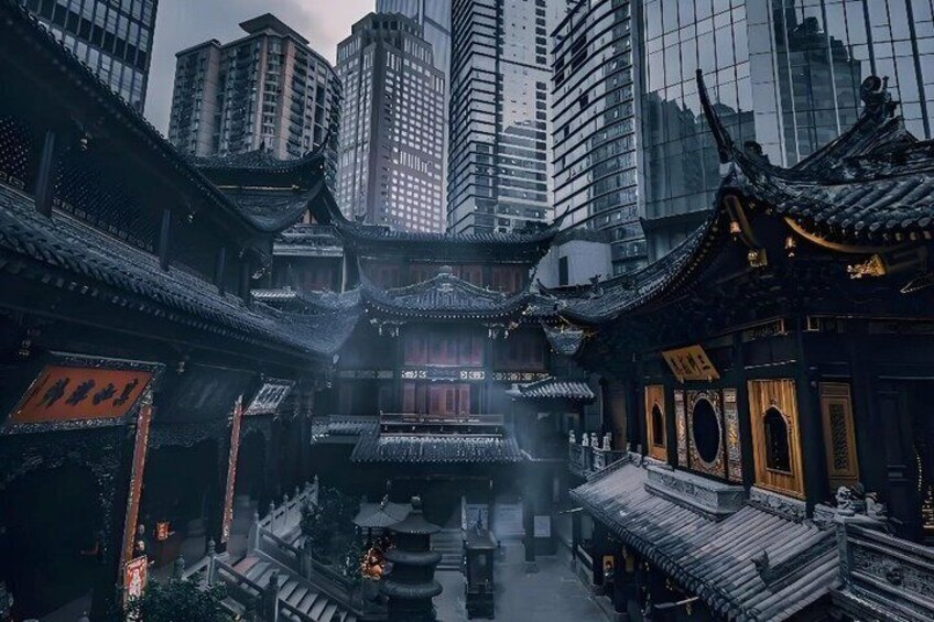 A traditional Chinese courtyard with ornate architecture, surrounded by modern high-rise buildings. 1