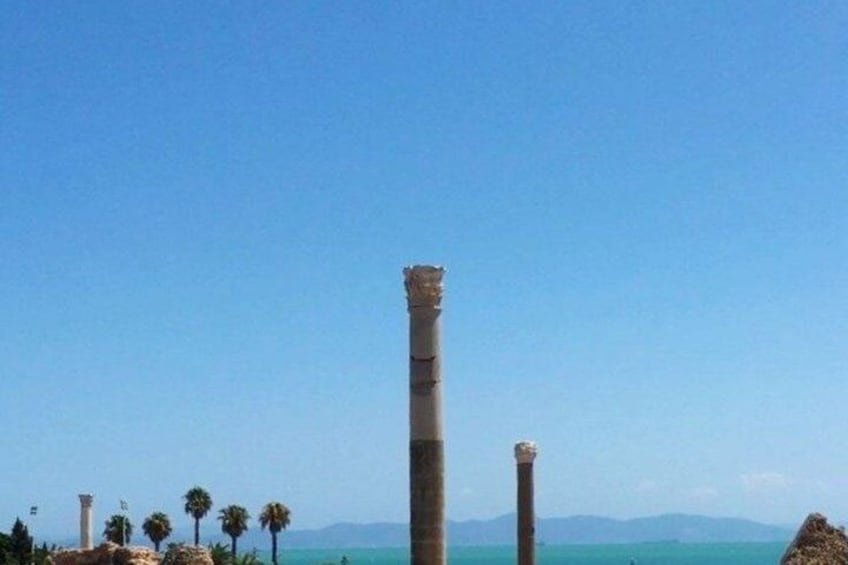 Ancient columns, a clear blue sky, and a distant mountain range. 1