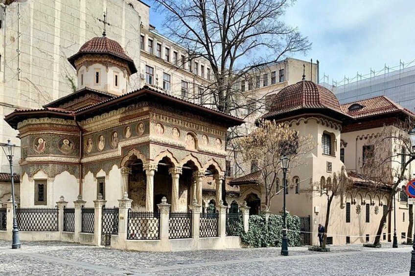 A historical building with ornate architecture, a cobblestone street, and a modern building in the background. 4