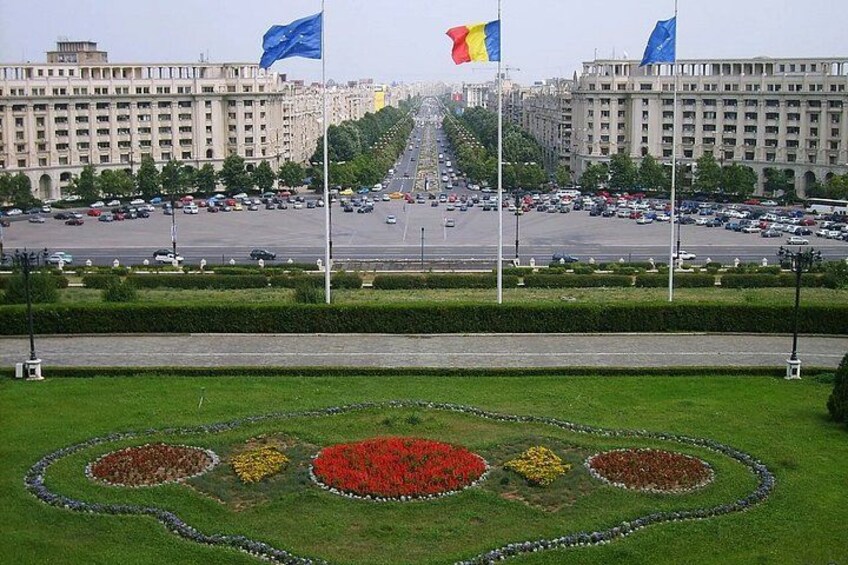 A cityscape with a central road, buildings, and a flower garden. 2