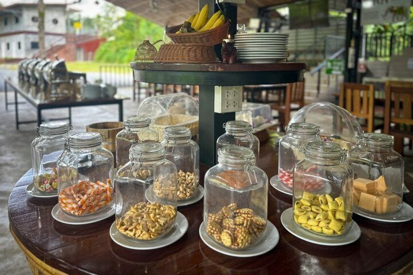 A buffet table with various food items in glass jars and plates. 3