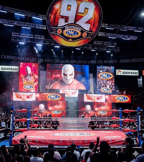 A wrestling ring with CMML logos, a large '92' sign, and a crowd watching. 1