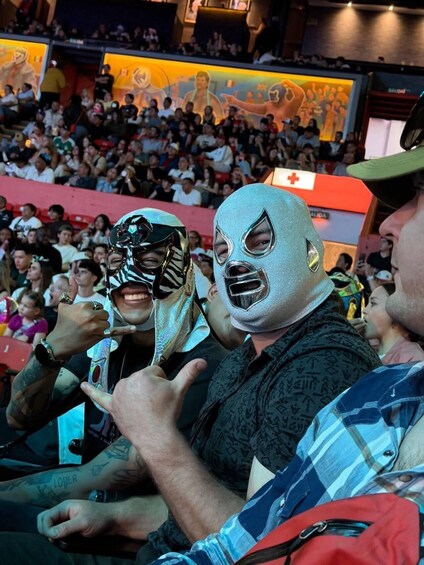 A crowded indoor event with people wearing masks and a red cross sign in the background. 3