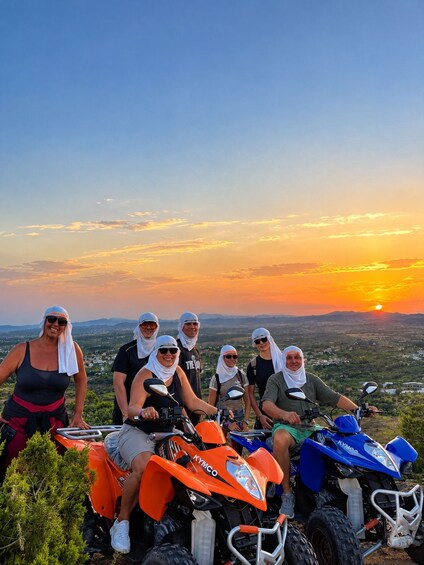 A group of people on ATVs with a sunset in the background. 5