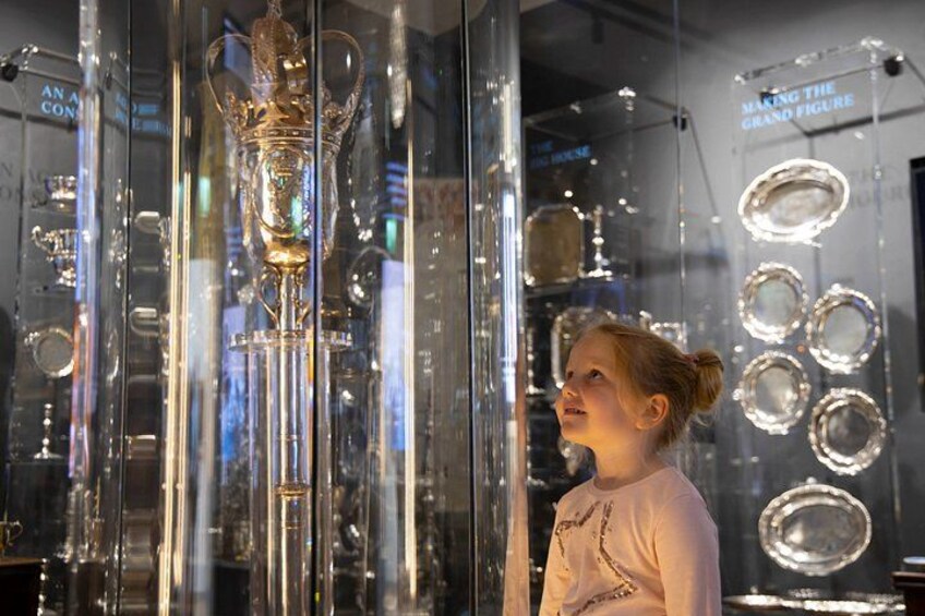 A person standing in front of a display of glass objects, including a large trophy and several circular glass pieces. 1