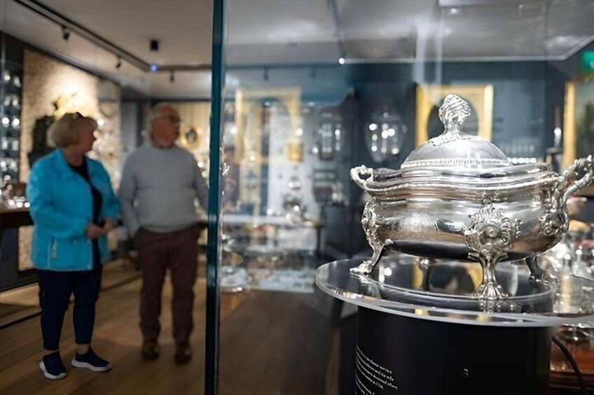 A silver ornate urn on display in a store with glass walls. 3