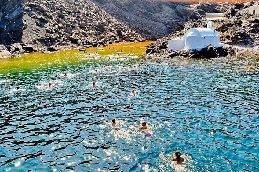 A natural pool with people swimming, surrounded by rocky terrain and a white building. 4