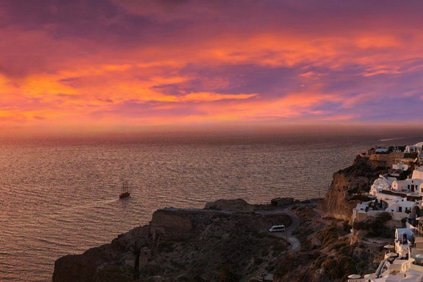 A coastal landscape with white buildings, a boat on the water, and a sunset. 1