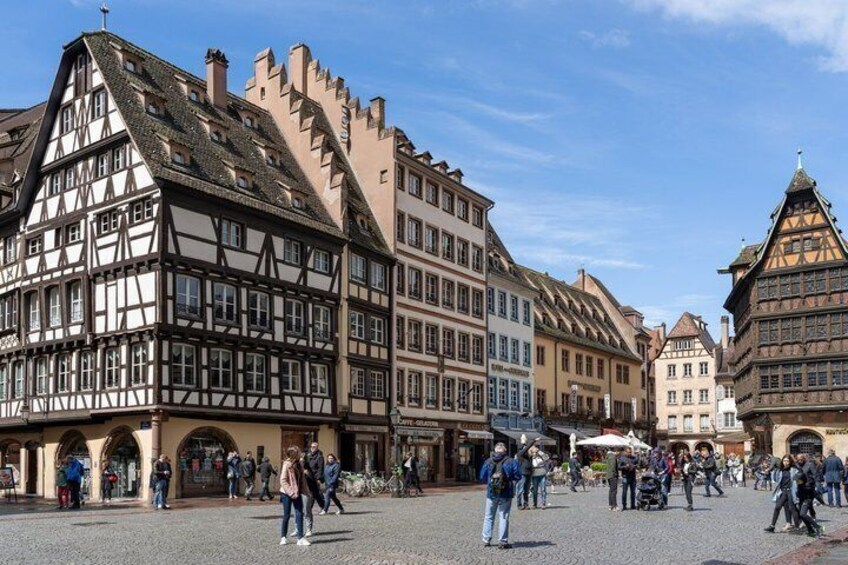 A historic European square with traditional half-timbered buildings and pedestrians. 2