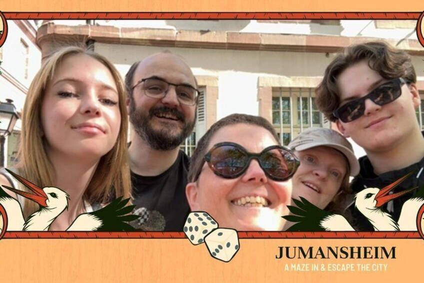 A group of people in front of a building with a sign that reads 'JUMANSHEIM A MAZE IN & ESCAPE THE CITY.' 5
