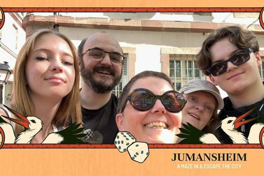 A group of people in front of a building with a sign that reads 'JUMANSHEIM A MAZE IN & ESCAPE THE CITY'. 5