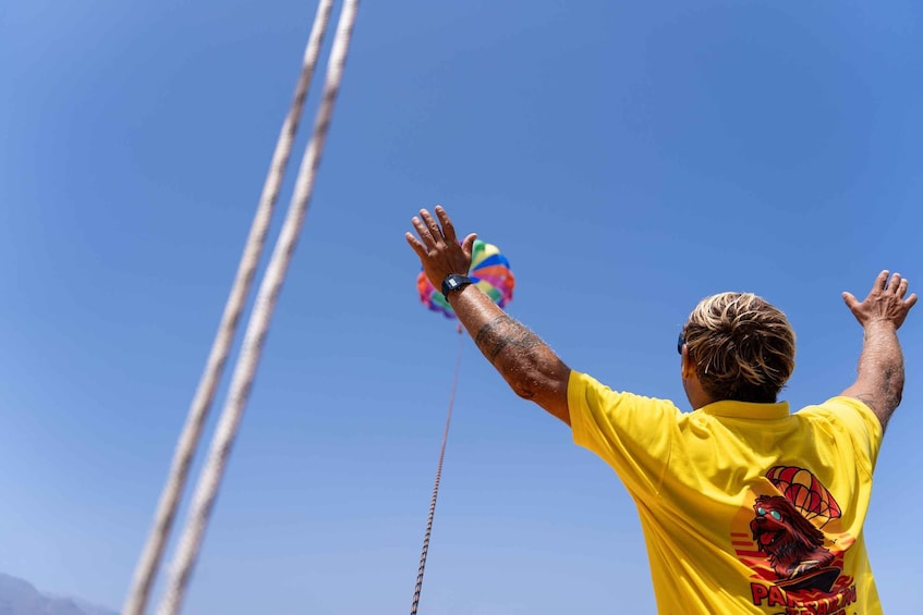 A person in a yellow shirt flying a kite with a colorful design. 5